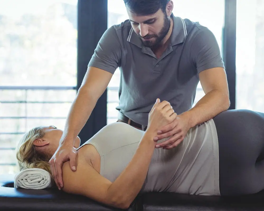 A man is stretching the woman 's leg.