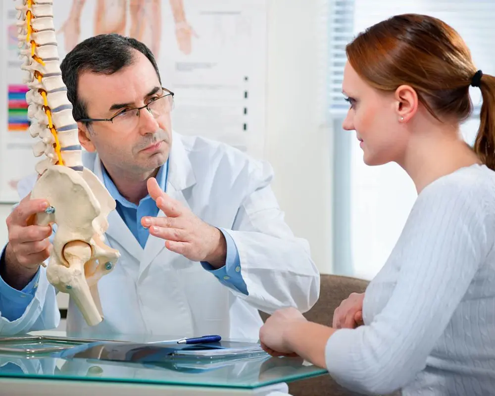 A doctor talking to a woman in an office.