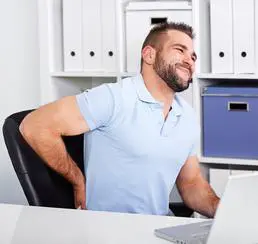 A man sitting at his desk with back pain.